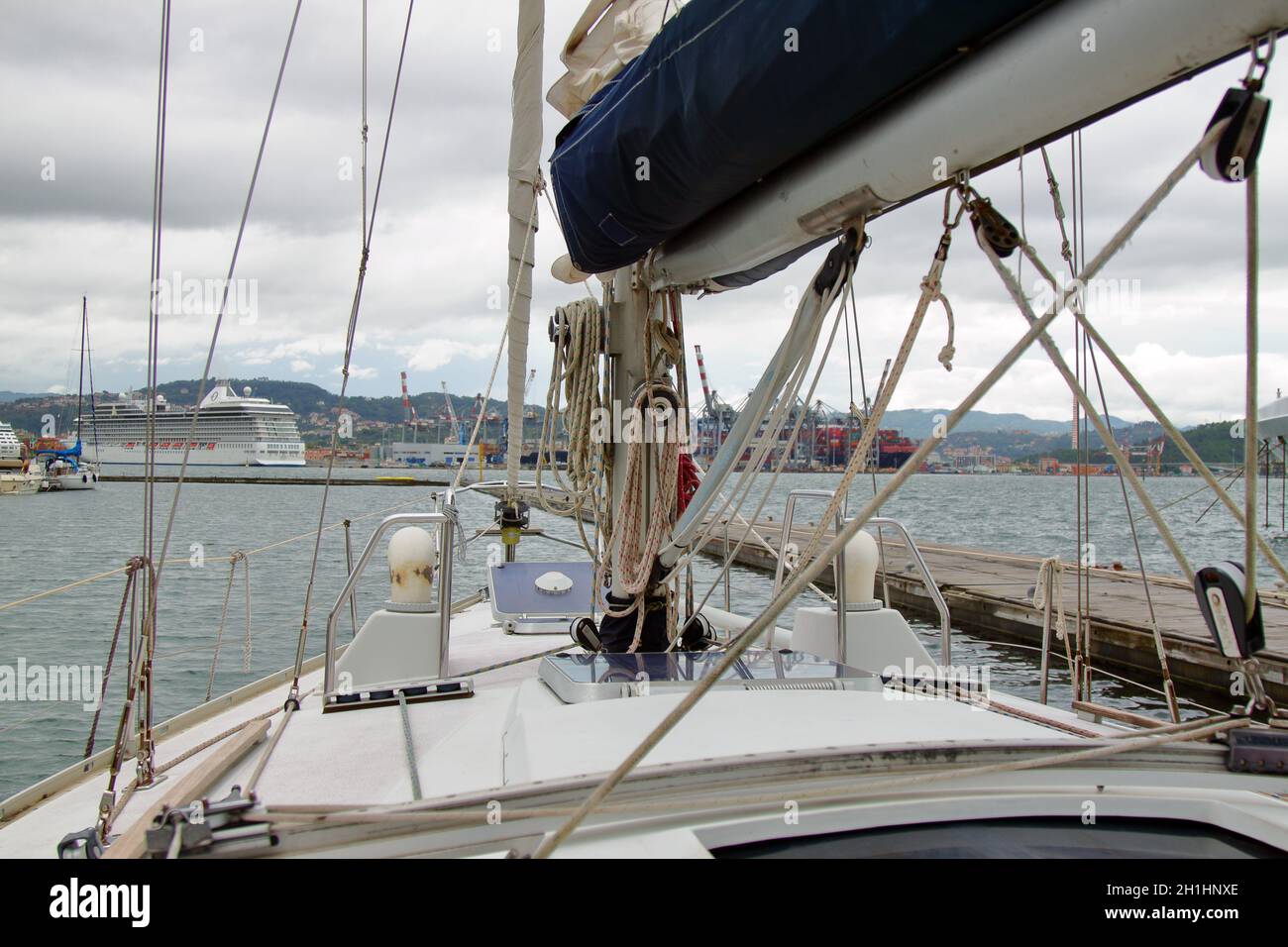 Nahaufnahme des Bogens eines Segelbootes, der am Hafen festgemacht ist, mit einem Kreuzschiff im Hintergrund. Hochwertige Fotos Stockfoto