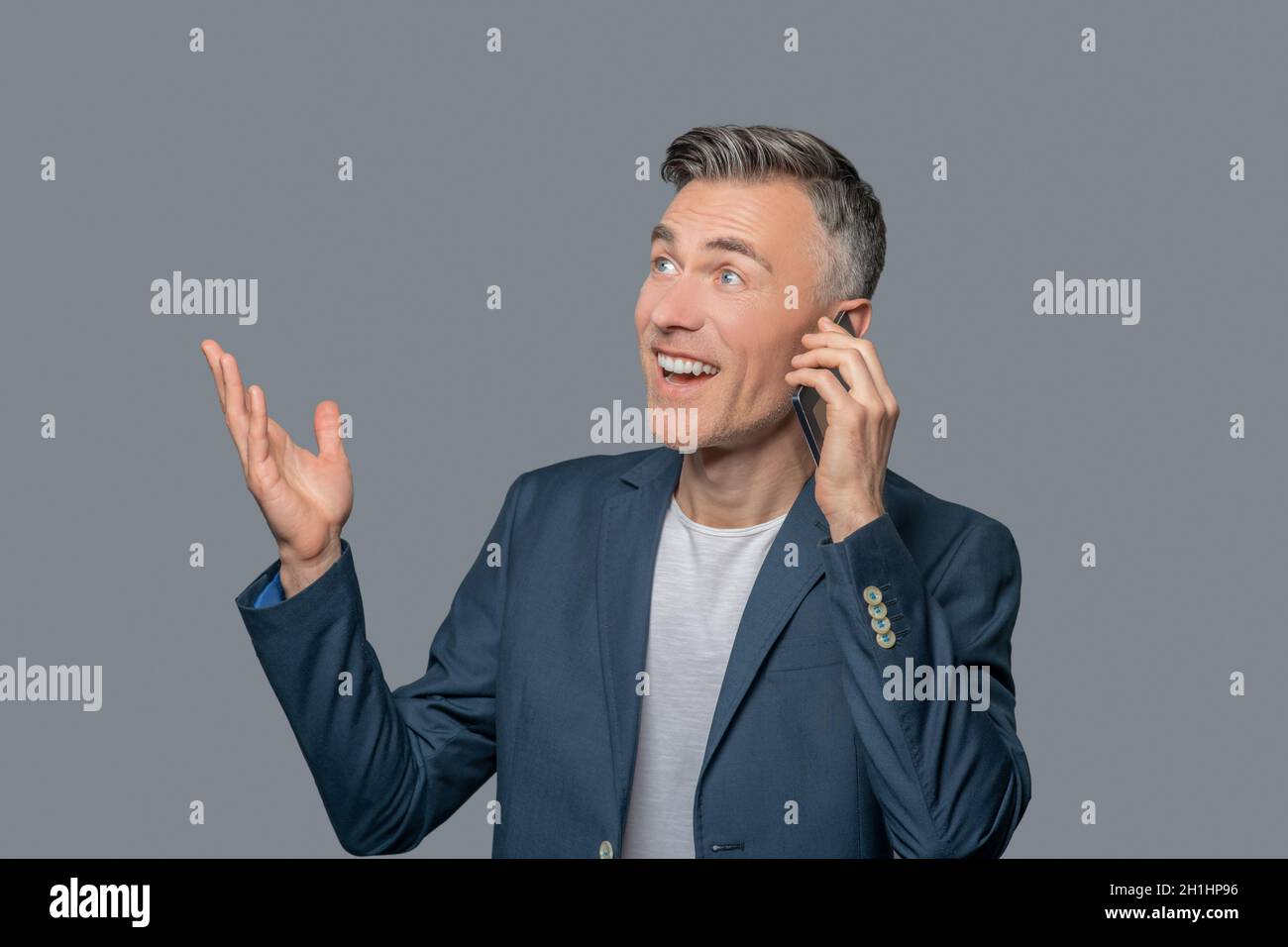 Emotionaler fröhlicher Mann, der auf dem Smartphone spricht Stockfoto