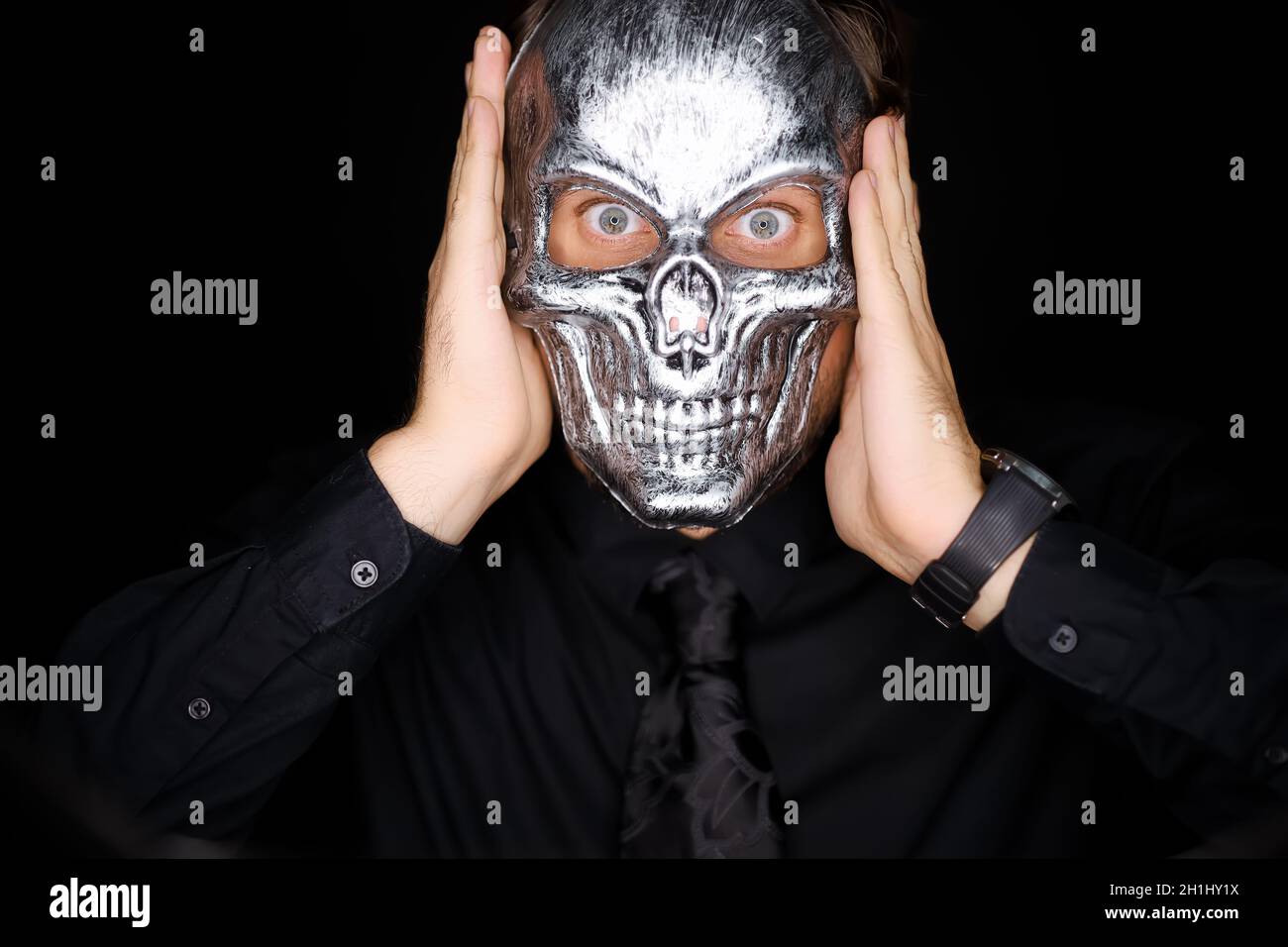 Ein Mann hält eine Skelettmaske vor sich Stockfoto