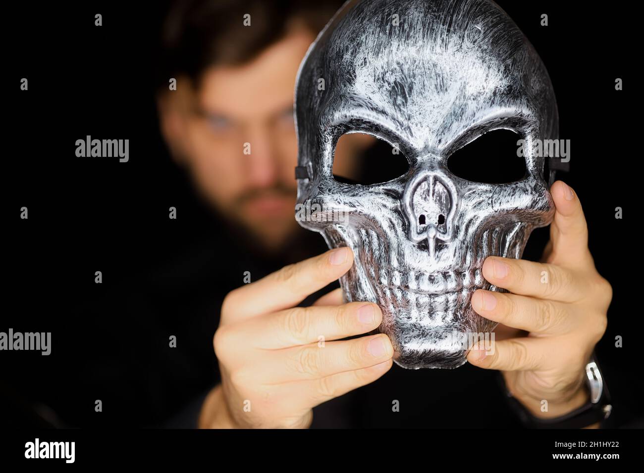 Ein Mann hält eine Skelettmaske vor sich Stockfoto