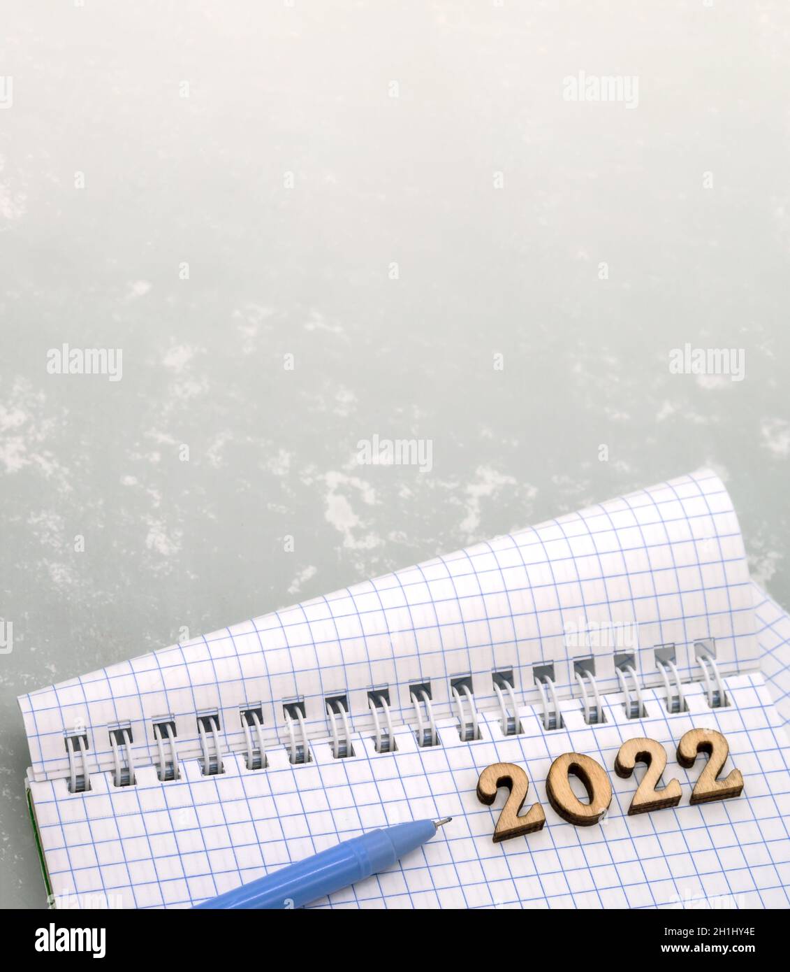 Notizbuch und Stift auf der grauen. Holznummern datieren 2022. Ein leeres Blatt Papier und ein blauer Stift. Stockfoto