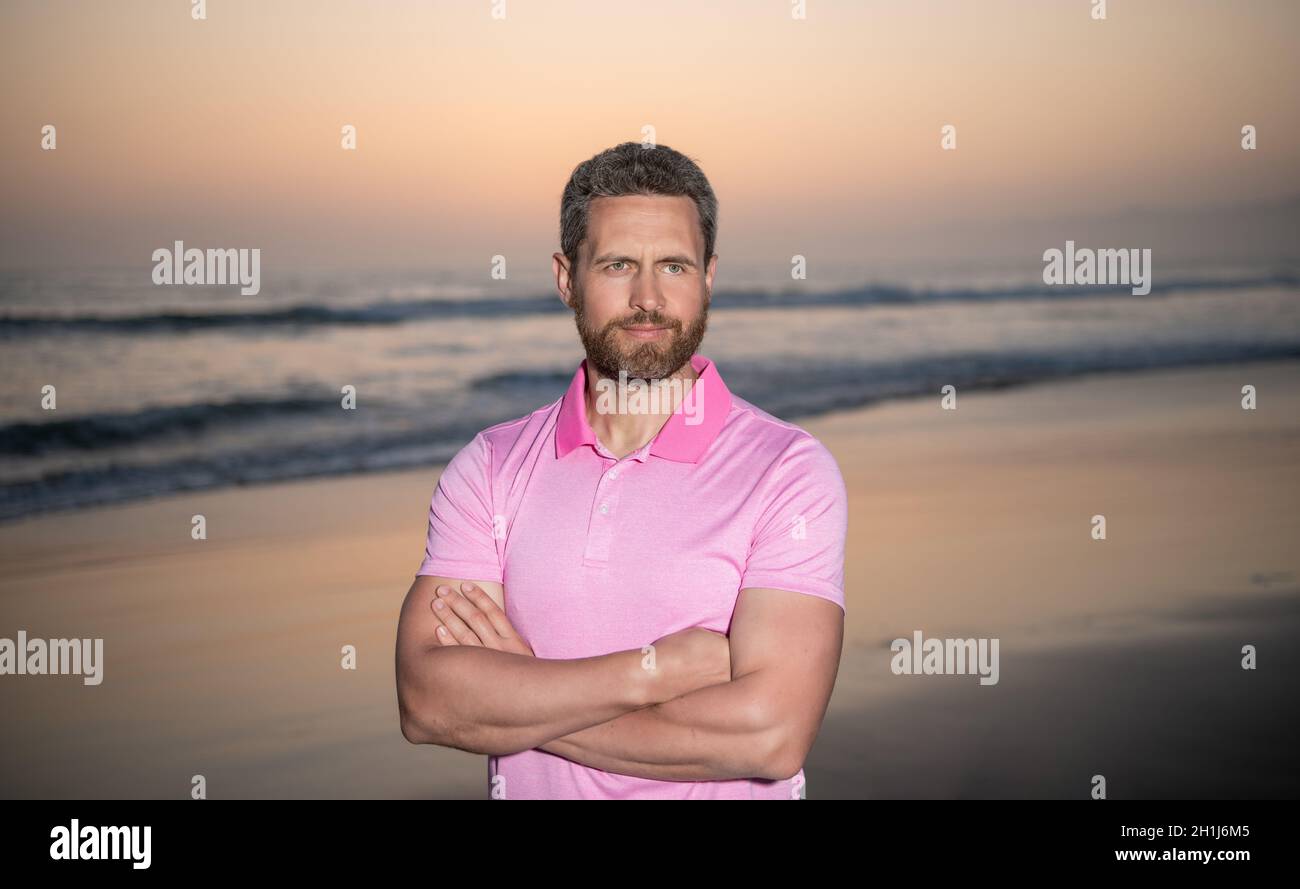 Sommerurlaub. Schöner Mann mit Bart im Sonnenuntergang über dem Meer. Unrasiert Kerl am Morgen Strand Stockfoto