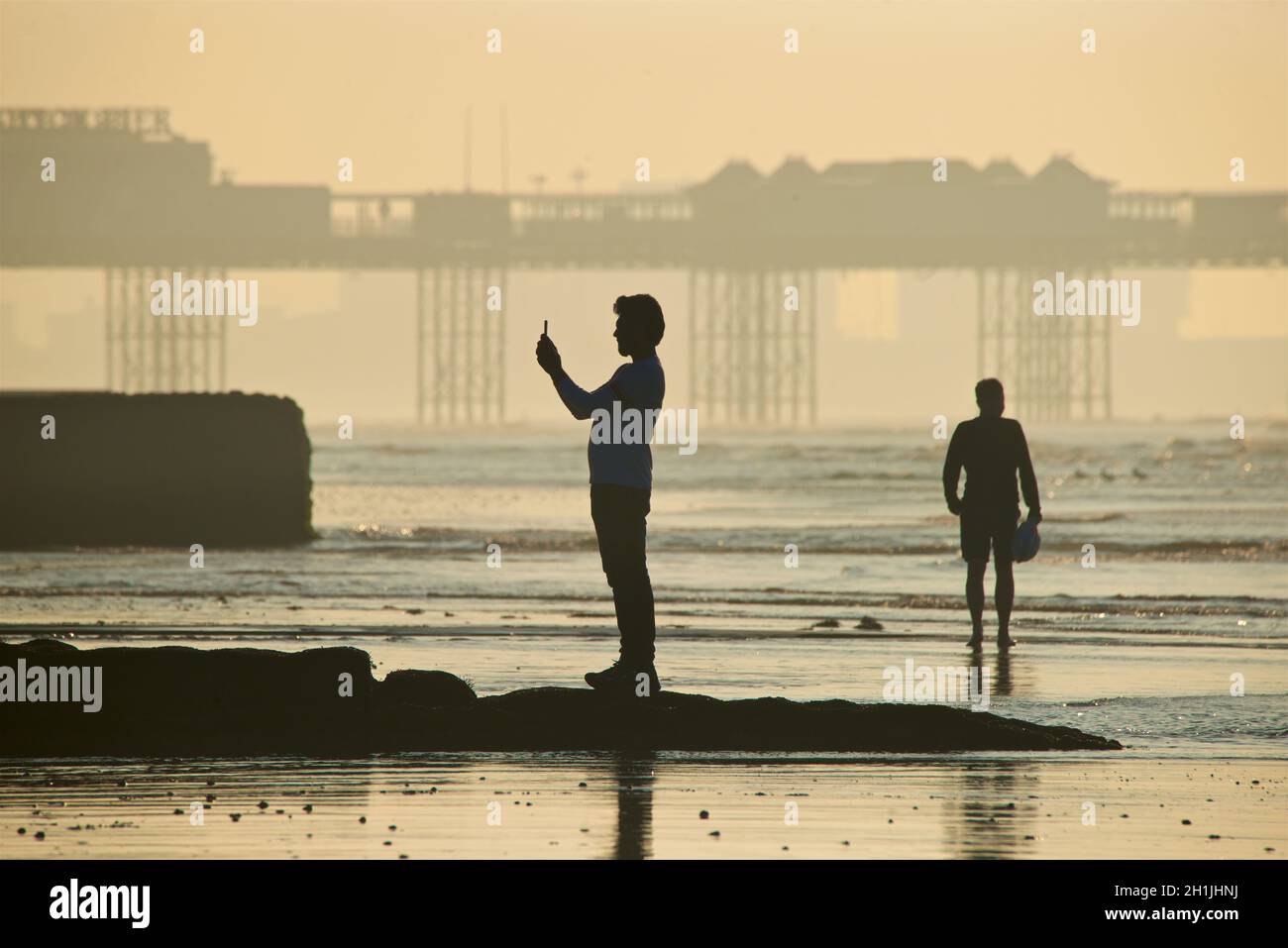 Brighton Beach bei Ebbe, Sonnenaufgang. Der Palace Pier im Hintergrund. Brighton & Hove, Sussex, England, Großbritannien Stockfoto