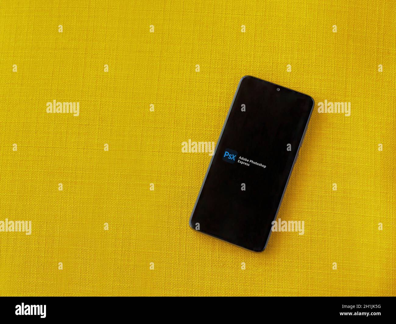 LOD, Israel - 8. Juli 2020: Adobe Photoshop Express Photo Editor App Play Store-Seite auf dem Display eines schwarzen Smartphone auf einem gelben Stoff BA Stockfoto