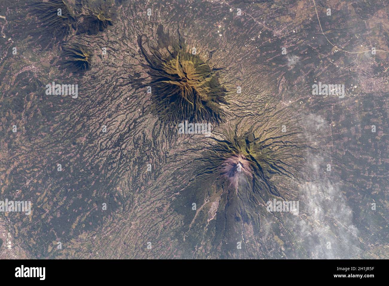 Die Erde von der Internationalen Raumstation aus gesehen: Ein rauchenden Berg Merapi (unten) und Mount Merbabu (oben), Java, Indonesien, 10. Mai 2021. Der Merapi ist ein hochaktiver Vulkan in Zentral-Java. Eine optimierte und verbesserte Version eines NASA-Bildes / Credit NASA. Stockfoto