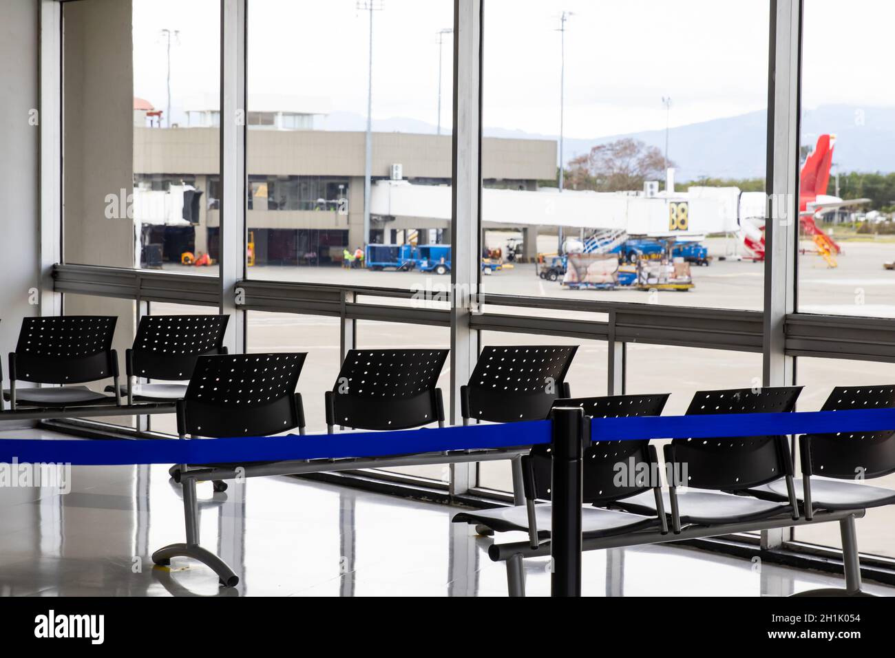 Leerer Warteraum an einem Flughafen während der COVID-19 Pandemie mit Soziale Distanzierungszeichen auf Stühlen Stockfoto