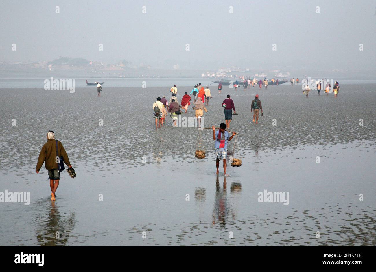 Bei Ebbe fällt das Wasser im Fluss Matla so tief, dass Menschen zum anderen Ufer in Canning Town, Indien laufen Stockfoto
