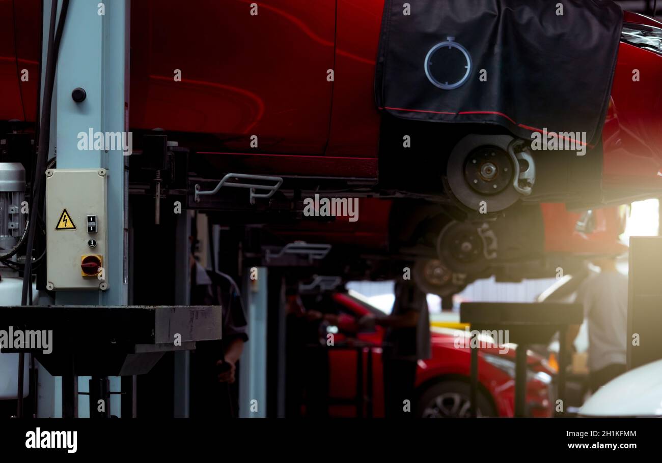 Selektiver Fokus auf Lift in Autowerkstatt. Rotes SUV-Auto in der Garage für Reparatur-und Wartungsservice angehoben. Auto-Check-up an der Tankstelle bei m Stockfoto