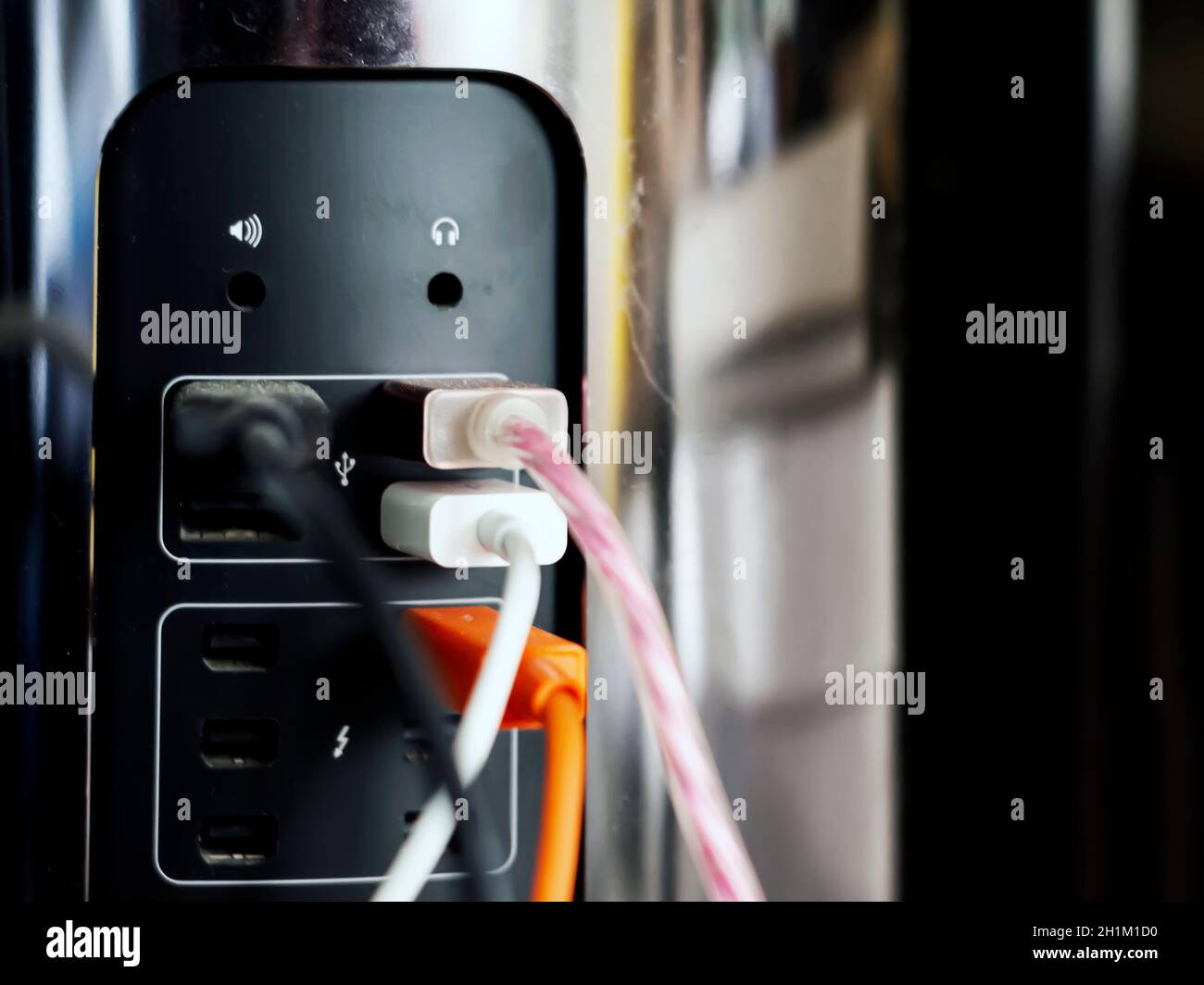 USB-Kabel, die an der Rückseite eines Computers mit den leeren Anschlüssen für Lautstärke und Kopfhörer angeschlossen sind. Technologie- und Hardwareverbindungen Stockfoto