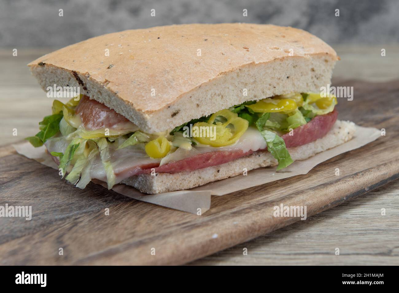 Ein riesiges Frühstückssandwich mit Fleisch, Salat, Gemüse und geschmolzenem Käse für einen herzhaften Start in den Tag. Stockfoto