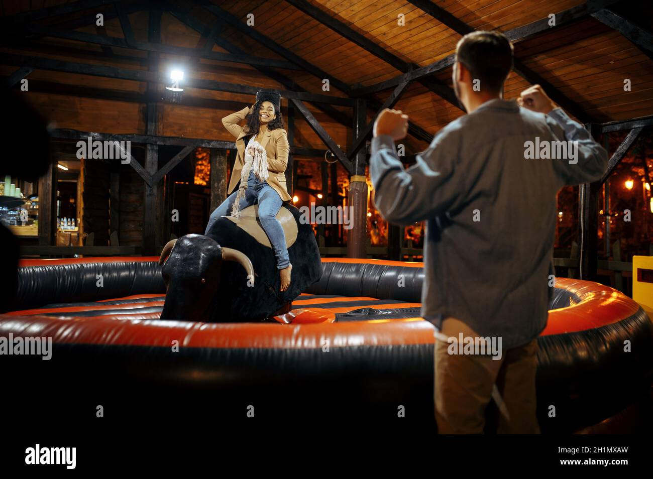 Ich liebe ein Paar auf Rodeo-Attraktionen im Nachtvergnügungspark. Entspannung für die ganze Familie auf dem Messegelände im Freien. Mann und Frau sind auf Karussell, Unterhaltungsthema Stockfoto