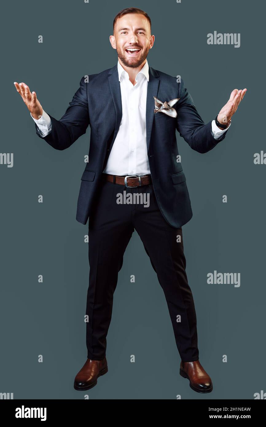 Ein fröhlicher Mann mittleren Alters in einer klassischen Jacke mit einer Emotion der Freude auf einem grauen Hintergrund. Porträt eines Geschäftsmannes oder Showman in vollem Wachstum. Stockfoto