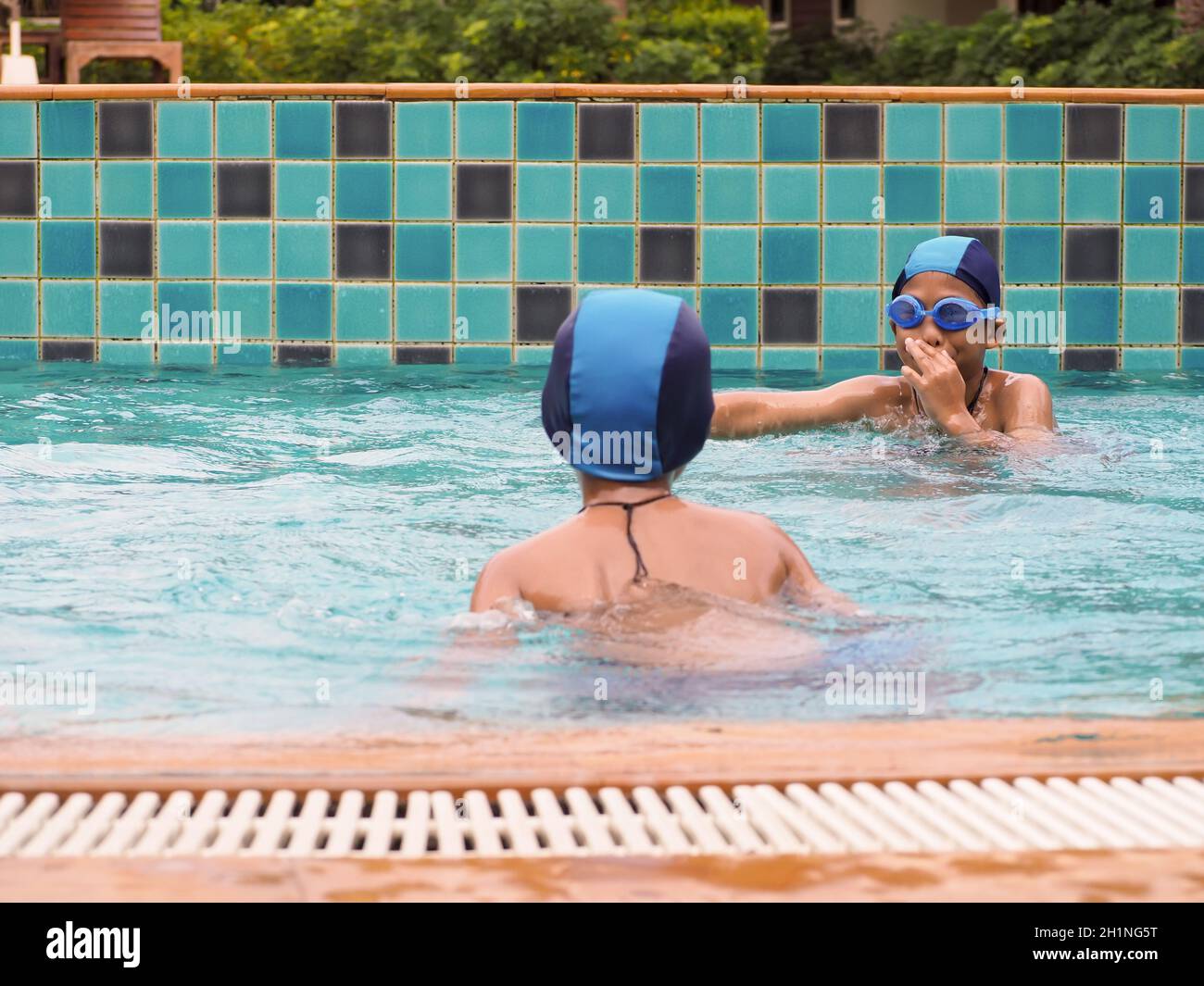 Mädchen und Jungen spielen im Pool Stockfoto