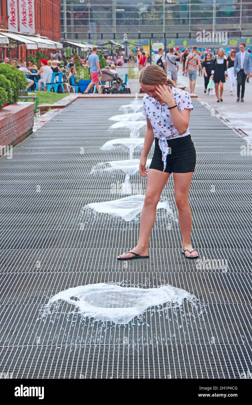 Kinder haben Spaß mit Stadtbrunnen während der Sommerhitze. Kinder spielen an heißen Sommertagen mit Wasserstrahlen. Hitze in der Stadt. Heißer Sommertag Stockfoto