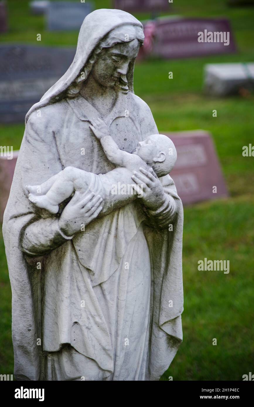 Bewegliche Statue einer steinernen Mutter und eines Babys. Das Baby hat eine Hand an der Mutter, aber die Augen sind geschlossen. Weiche, sanfte Hände sind schön. Off-Center-Witz Stockfoto