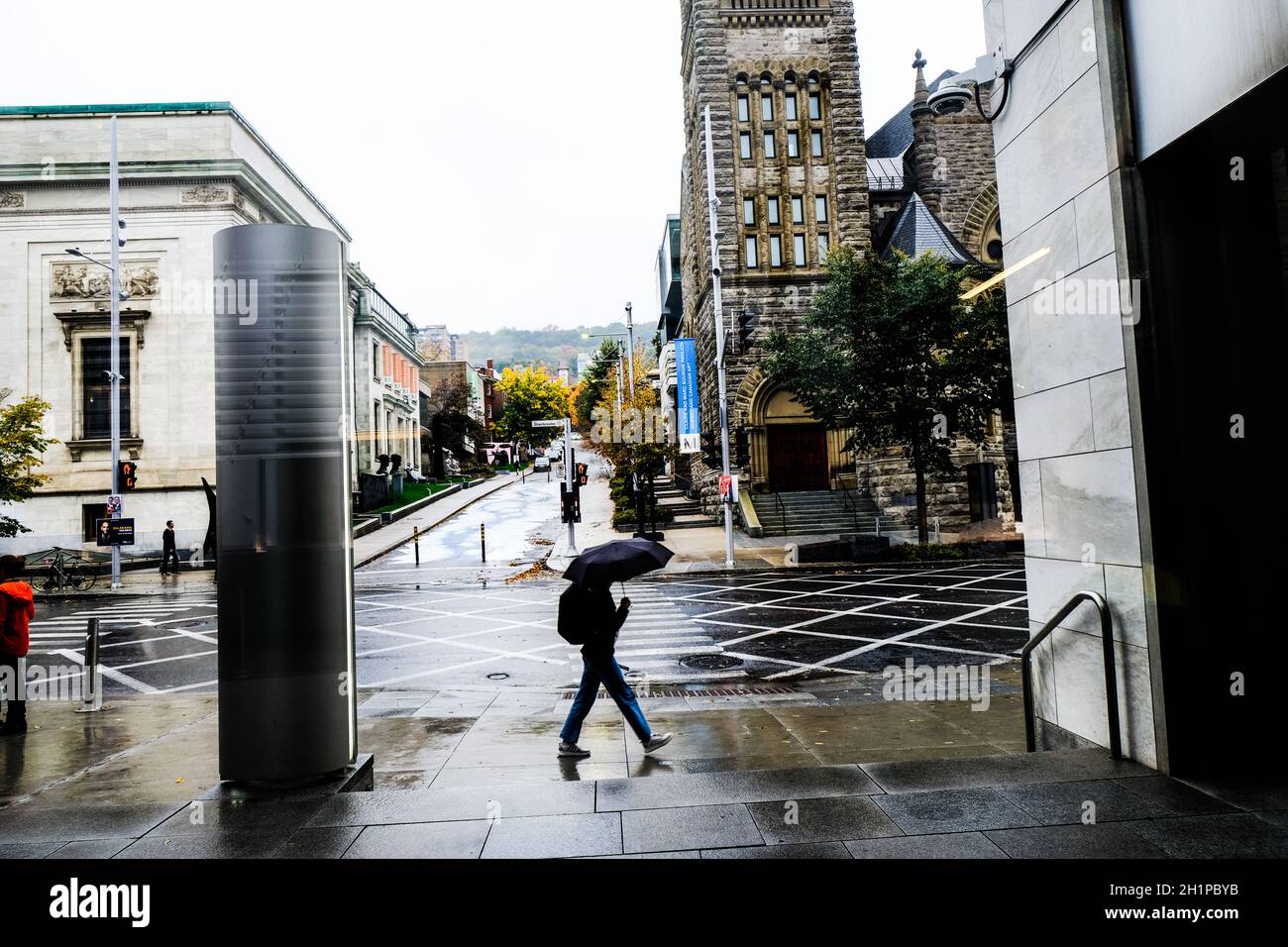 Fußgänger flanieren an einem regnerischen Tag auf der Sherbrooke Street in Montreal, Quebec, Kanada, in der Nähe des Montreal Museum of Fine Arts Stockfoto