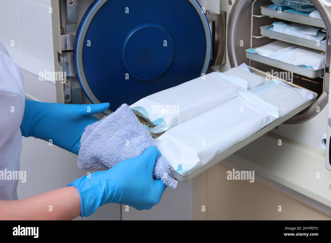 Ein Mitarbeiter der Zahnklinik nimmt aus dem Sterilisationsschrank bereits verarbeitete Instrumente in einer versiegelten Verpackung. Ein nicht erkennbares Foto. Co Stockfoto