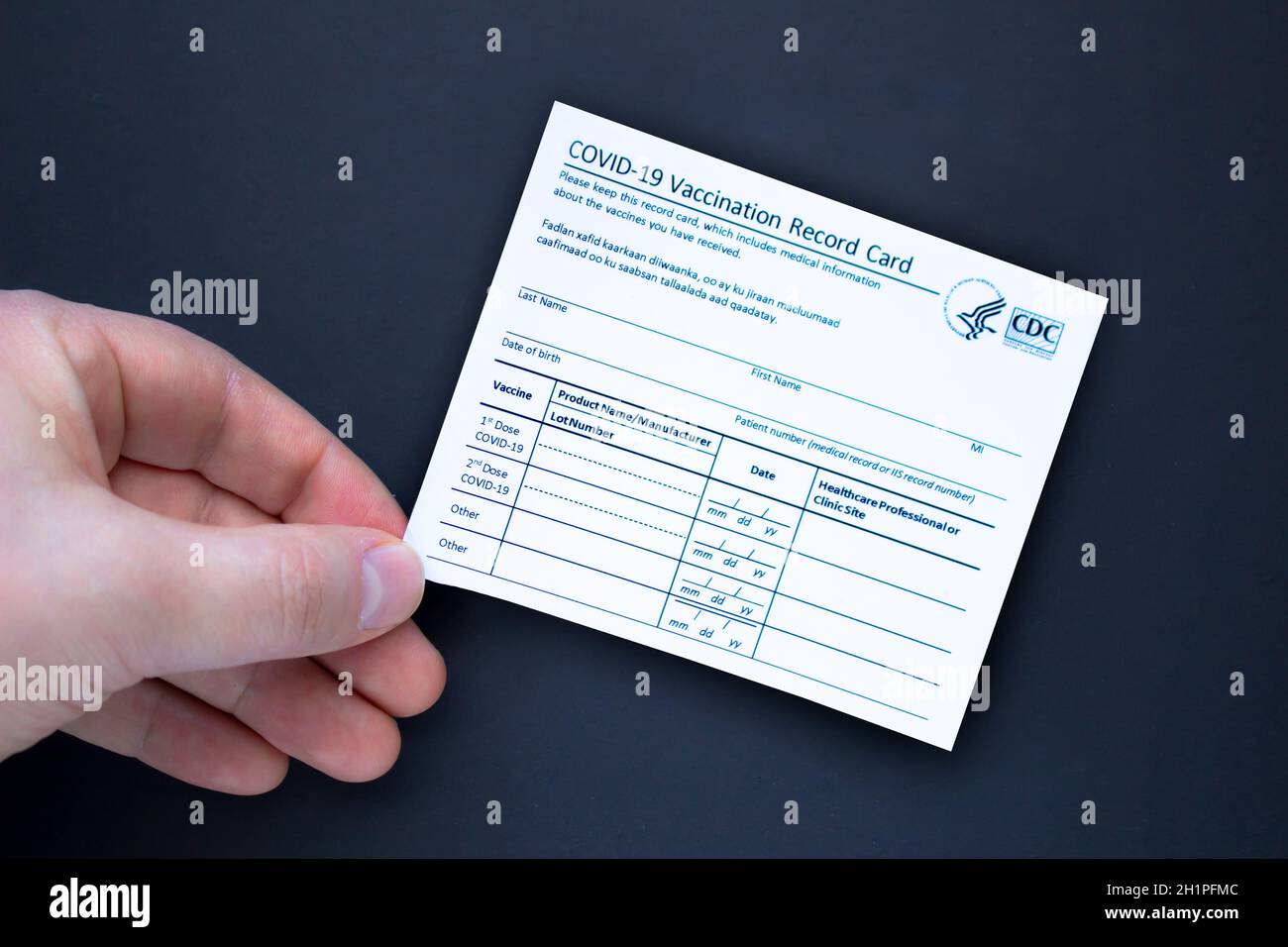 Calgary, Alberta. Kanada. Februar 3 2021. Eine Person mit einer COVID-19 Impfkarte auf schwarzem Hintergrund. Stockfoto