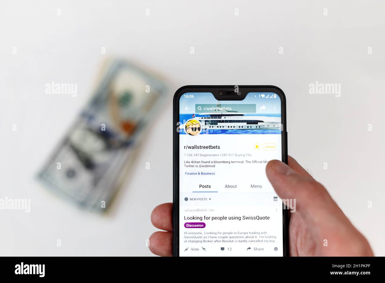 Minsk, Weißrussland - 31, Januar, 2021: Reddit-Logo auf Smartphone-Bildschirm in männlichen Händen mit Geld auf dem Tisch. Stockfoto