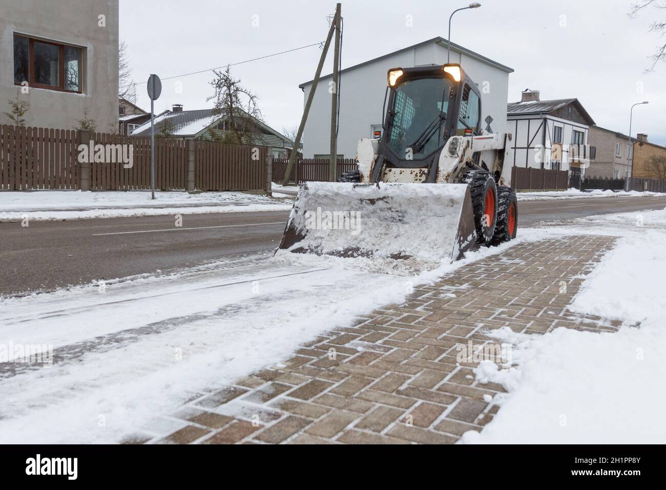 kleine Bagger Bobcat arbeitet an der Straßenreinigung, Schnee Stockfoto