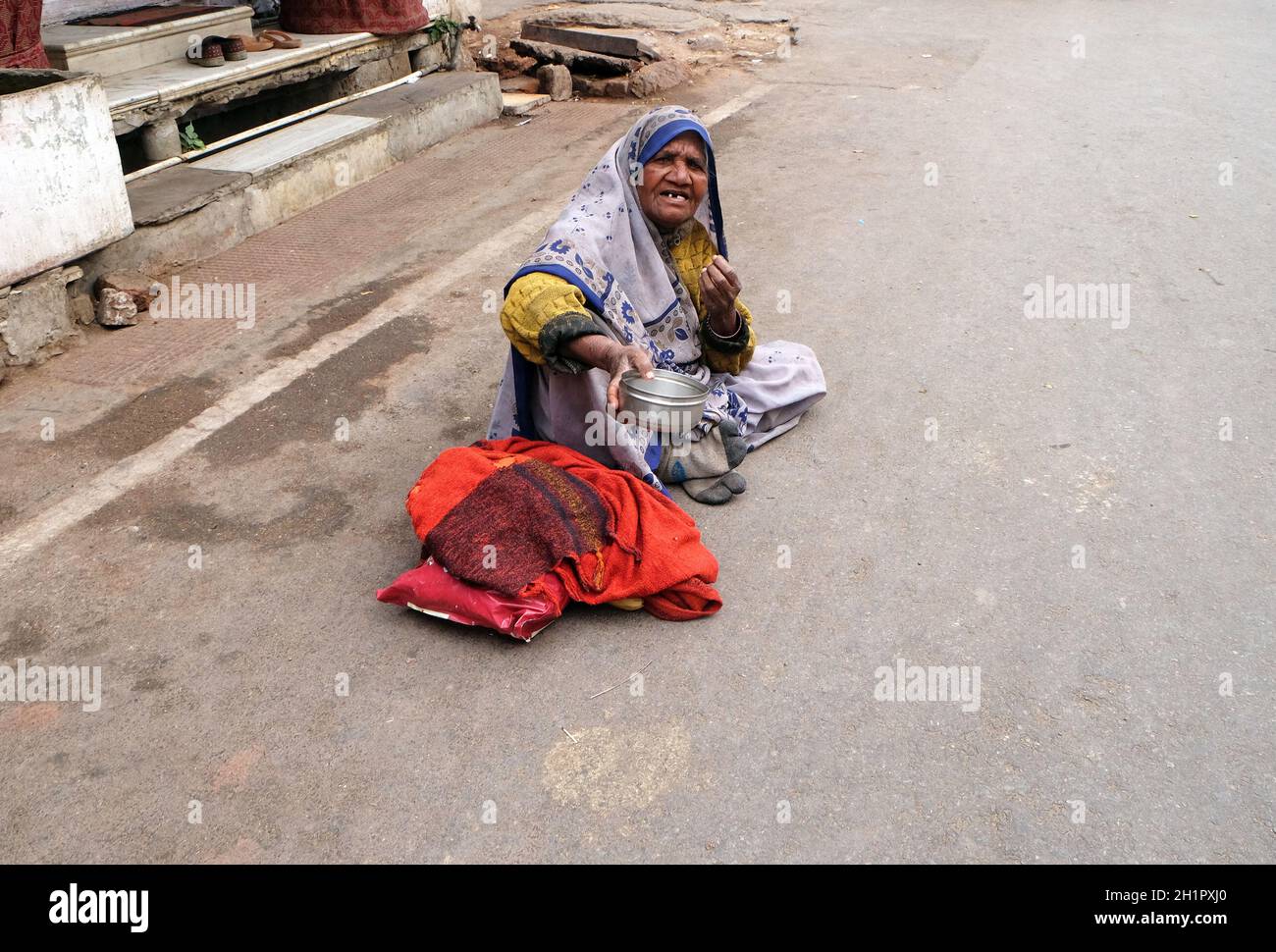 Der Bettler wartet auf Almosen auf einer Straße auf dem Ghat entlang des heiligen Sarovar-Sees in Pushkar, Indien Stockfoto