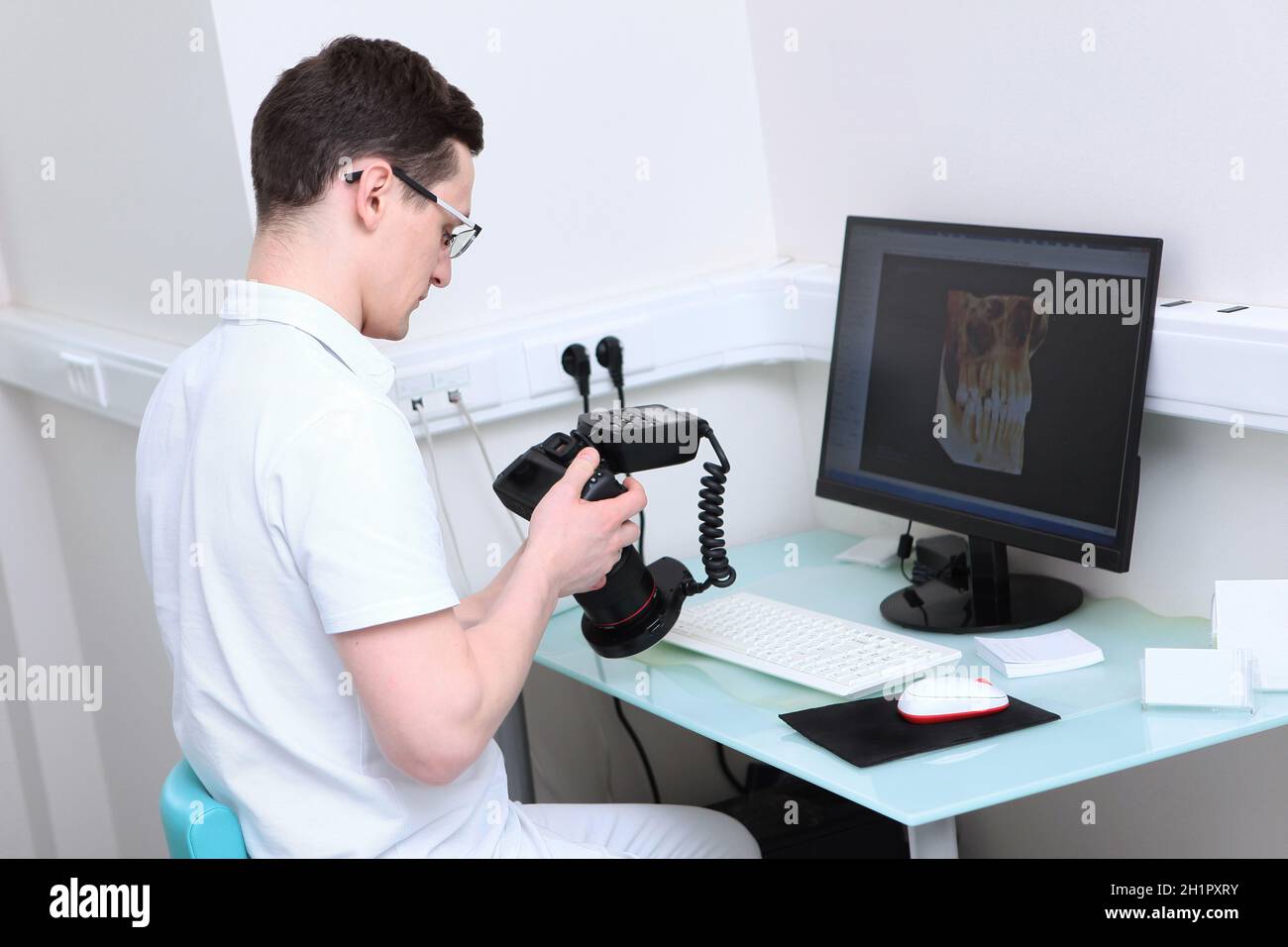 Der Zahnarzt hält eine Kamera mit einem Ringblitz in den Händen. Die Arbeit eines Arztes in einer Zahnarztpraxis. Bilder von Zähnen auf einem Computerbildschirm. Modern de Stockfoto