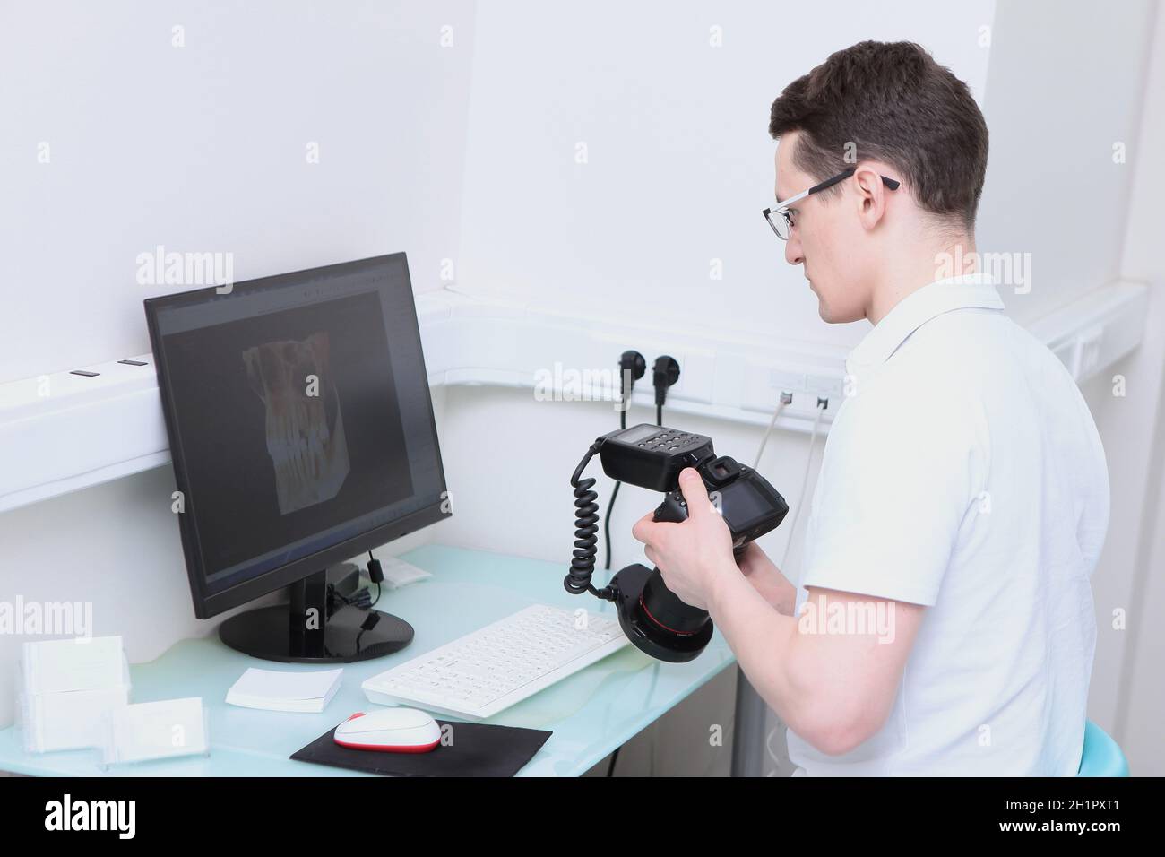 Der Zahnarzt betrachtet das 3D-Bild der Zähne am Computer. Eine Kamera mit einem Ringblitz in den Händen eines Arztes. Moderne Zahnarztpraxis. Speicherplatz kopieren. Stockfoto