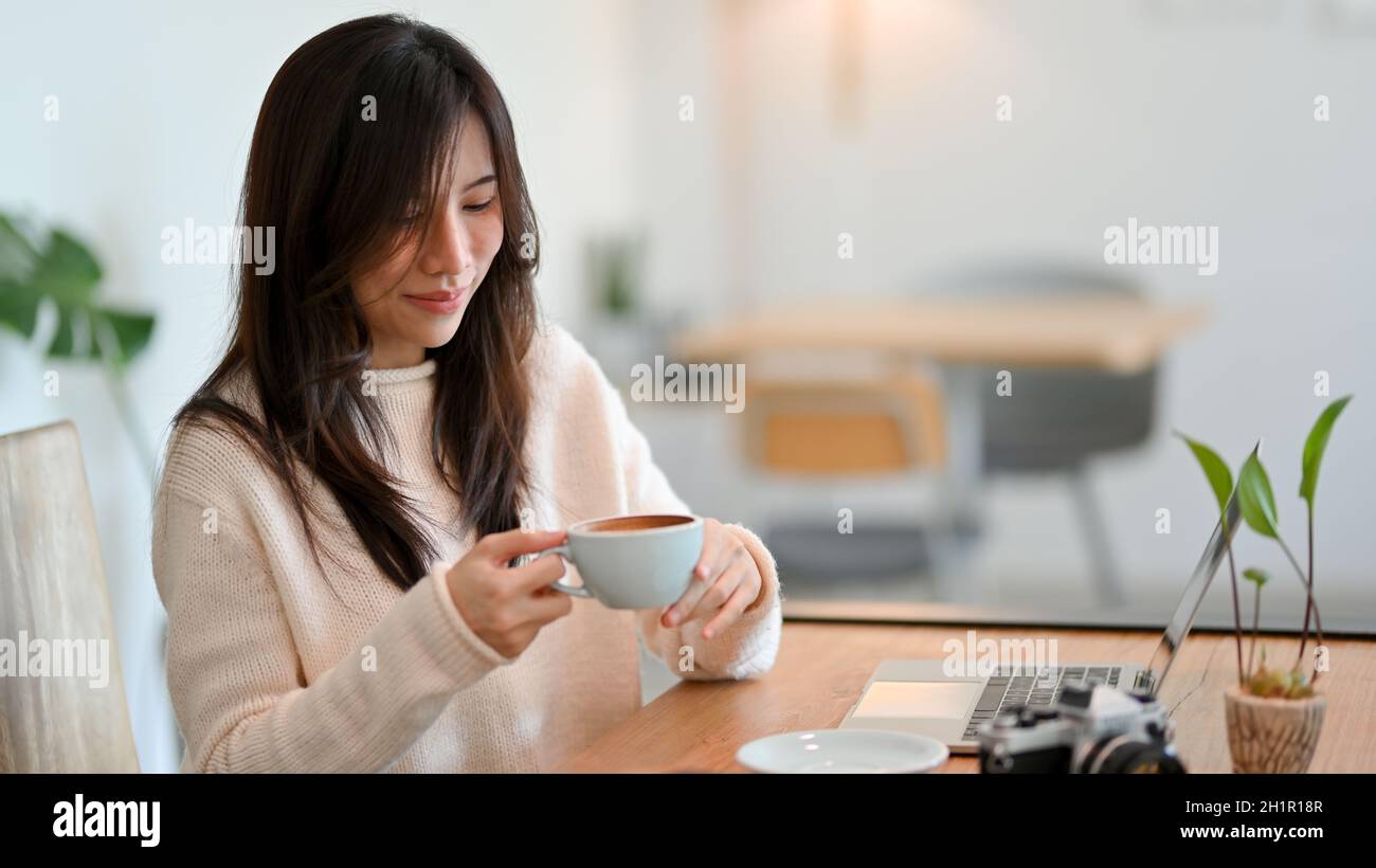 Attraktive junge Frau genießt ihren Morgenkaffee in einem Café Co-Working-Space. Entspannen Sie sich vor der Arbeit Stockfoto