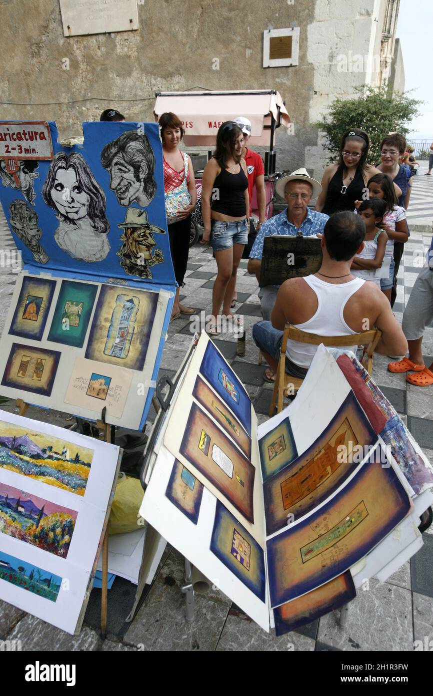 Ein Straßenkünstler und Maler auf einem Straßenmarkt in einer Gasse im Zentrum der Altstadt von Taormina in der Provinz Sizilien in Italien. Italien, Sizilien, Stockfoto