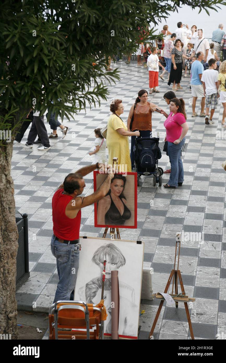 Ein Straßenkünstler und Maler auf einem Straßenmarkt in einer Gasse im Zentrum der Altstadt von Taormina in der Provinz Sizilien in Italien. Italien, Sizilien, Stockfoto