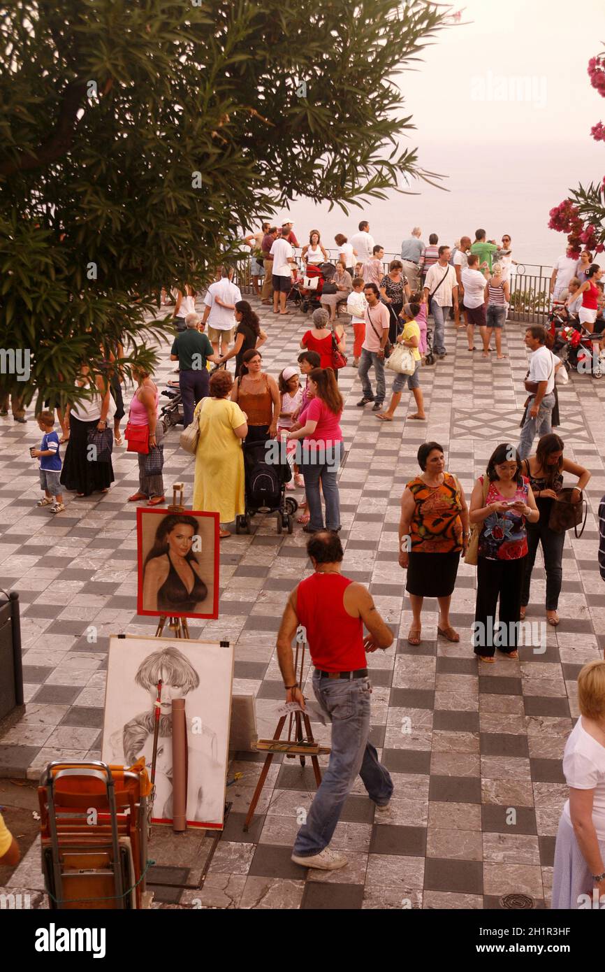 Ein Straßenkünstler und Maler auf einem Straßenmarkt in einer Gasse im Zentrum der Altstadt von Taormina in der Provinz Sizilien in Italien. Italien, Sizilien, Stockfoto