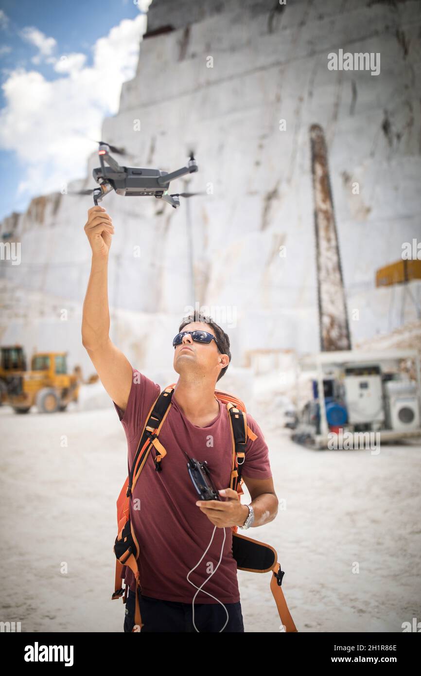 Junger Mann, der seine Drohne fliegt, nimmt Luftaufnahmen von einem Ort auf Stockfoto