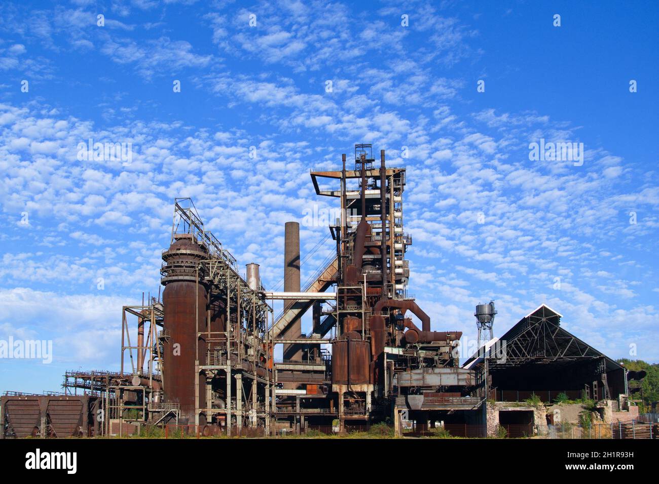 Verrostete und stillgelegte Industrie Barracke im Ruhrpott vor blauem Himmel mit Wolken im Sommer Stockfoto