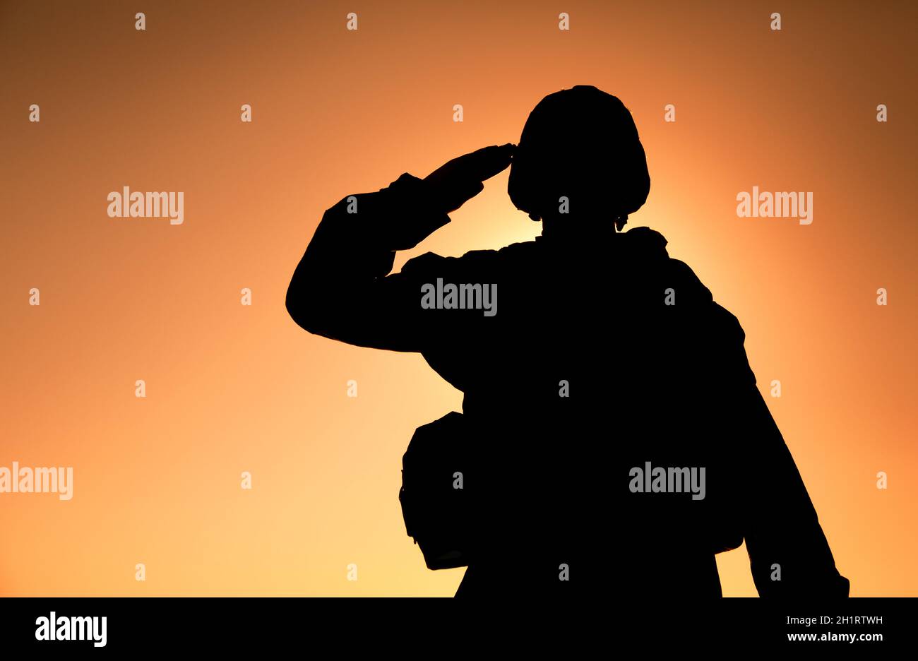 Die Silhouette des Soldaten im Kampfhelm und die auf dem Hintergrund des Sonnenuntergangs grüssende Munitionsmunition. Armee Spezialeinheiten Kämpfer, Marines Rifleman zeigt bzw. Stockfoto