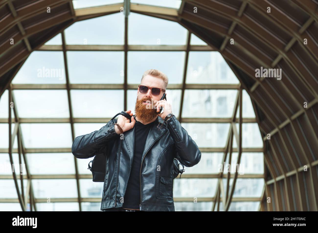 Stilvoll gekleideter junger Mann mit einem Bart, der am Telefon spricht Stockfoto