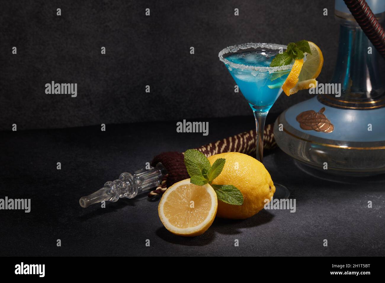 Shisha und ein Glas Blue curacao Cocktail mit Zitrone und Minze auf dunkelgrauem Hintergrund. Shisha Bar. Wochenende oder Feiertagsparty Stockfoto