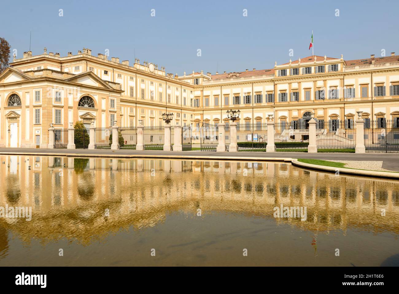 westansicht des monumentalen neoklassizistischen Gebäudes der Villa reale, das in einem großen Brunnen reflektiert wird, aufgenommen in hellem Licht in Monza, Lombardei, Italien Stockfoto