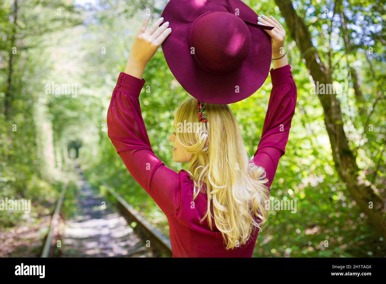 Schöne Mädchen in Cherry Kleid mit Hut im Wald Stockfoto