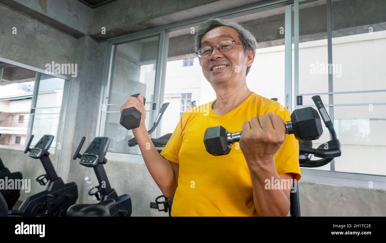 Porträt eines Senioren mit einer Brille, der im Fitnessstudio trainiert. Stockfoto