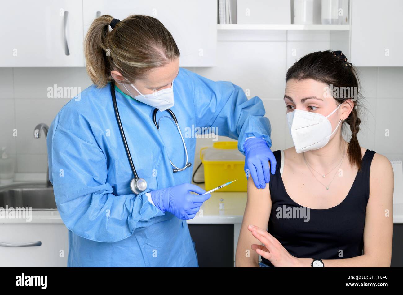 Junge Frau in Gesichtsmaske Angst vor Coronavirus-Impfstoff, nicht zulassen, Arzt Injektion in der Klinik. Frau hat Angst vor einer Covid-19-Impfung. Immunisierung Stockfoto