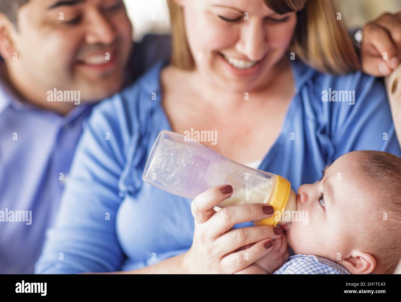 Gerne attraktive Mixed Race Paar mit der Flasche füttern ihren Sohn. Stockfoto