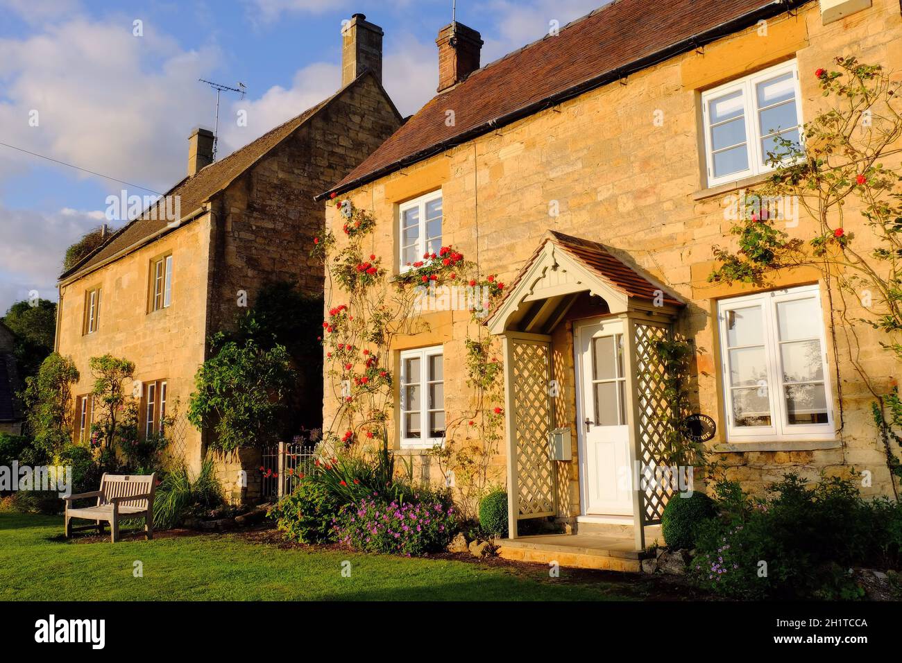 Zwei Cotswold-Steinhütten, die kurz vor Sonnenuntergang orange leuchten, in Stanton, Cotswolds, Gloucestershire, England Stockfoto