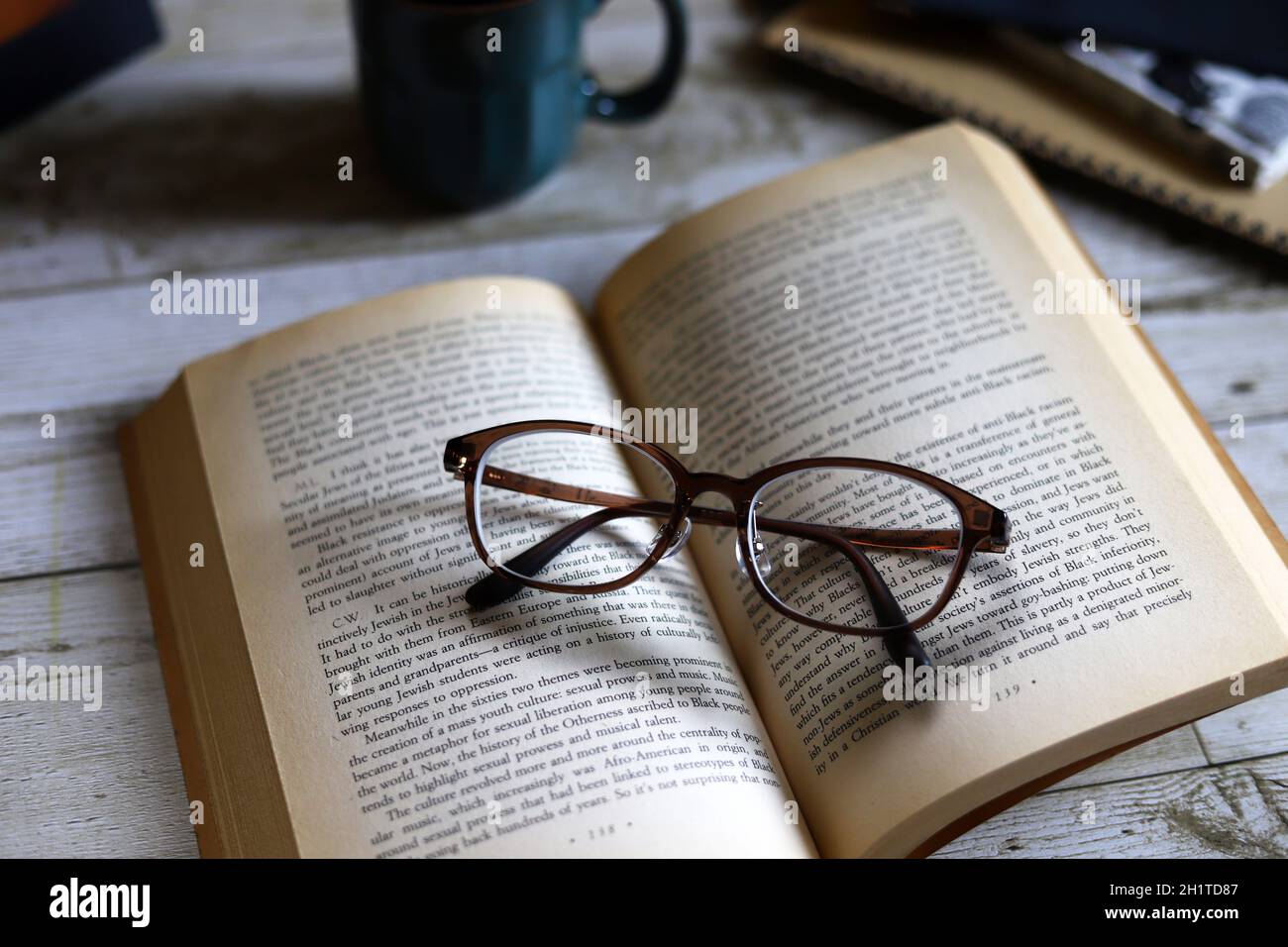 Taschenbuch und Augengläser, Lesen beim Kaffeetrinken, entspannende Zeit Stockfoto