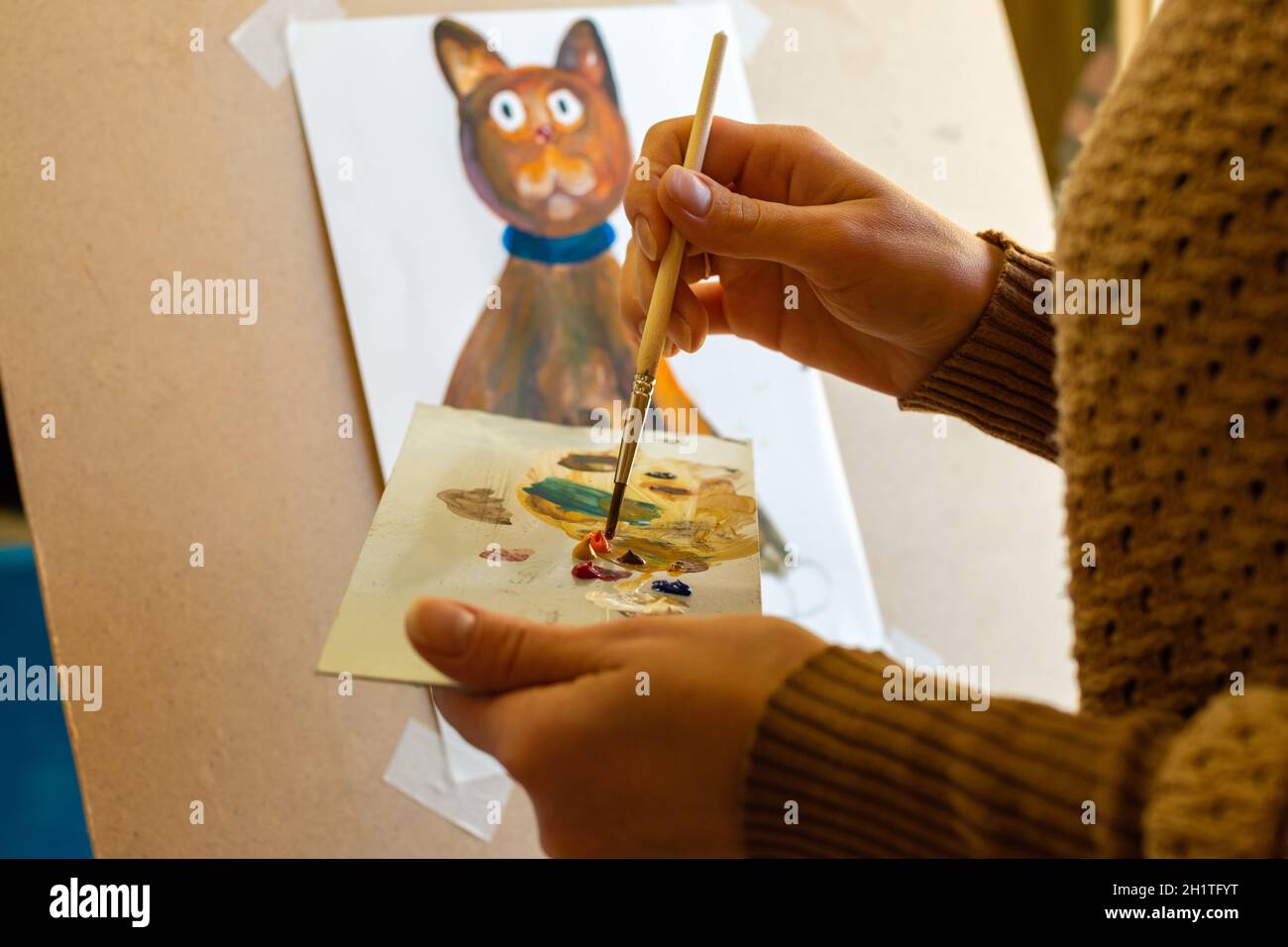 Porträt des Künstlers bei der Arbeit, die Hände eines Mädchens auf einer Palette mit einem Pinsel mischt Farben Stockfoto