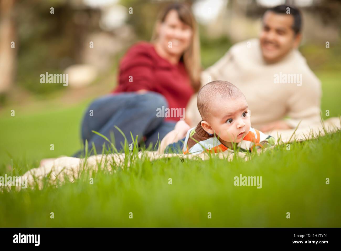 Glücklich krabbelnden Baby Boy und Mischlinge Eltern spielen im Park. Stockfoto