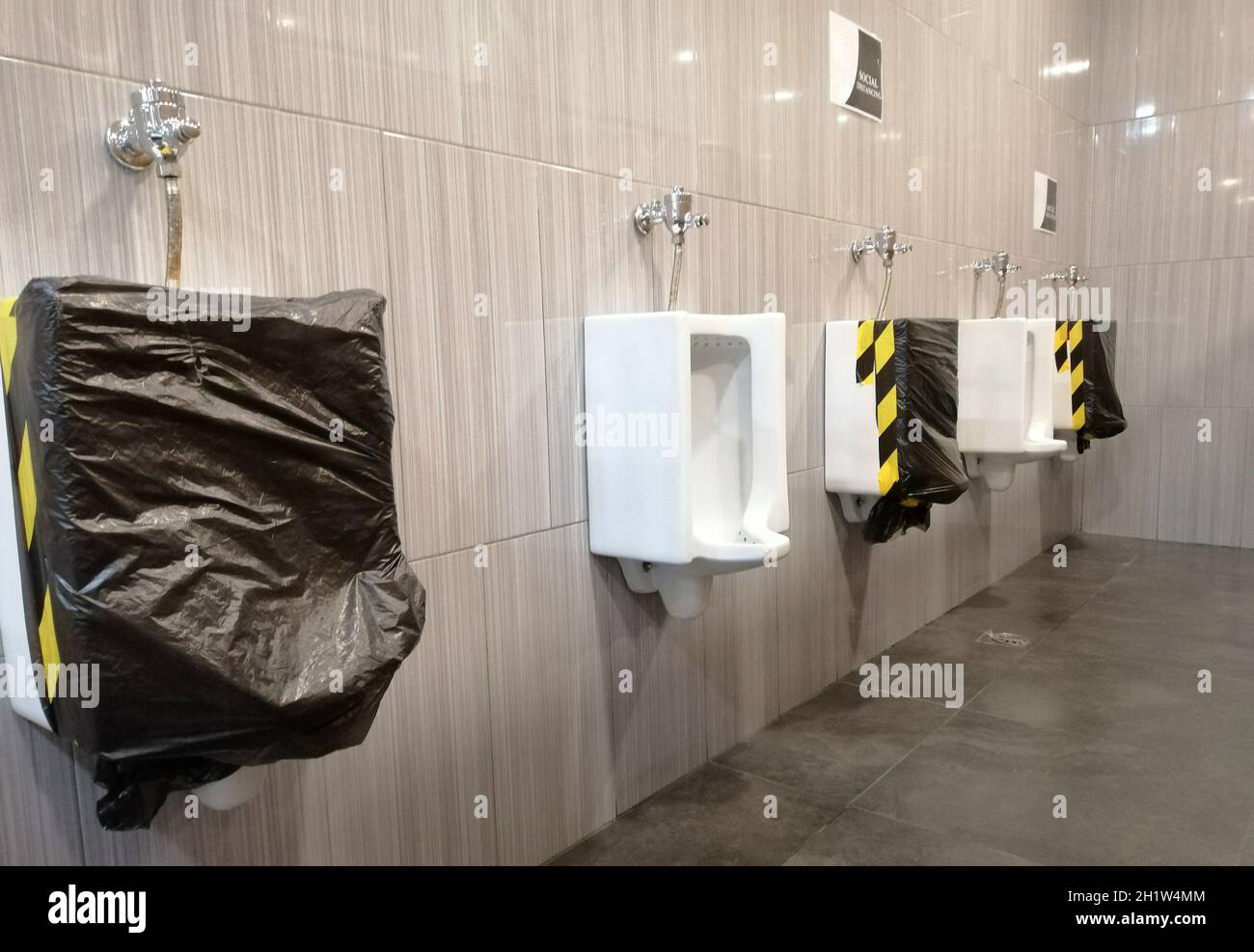 Öffentliche Männer Toilette während der Corona-Virus-Pandemie. Neue Normalität, dass Menschen soziale Distanz halten müssen, um eine Ausbreitung des Virus zu verhindern. Persönliche Hygiene, s Stockfoto