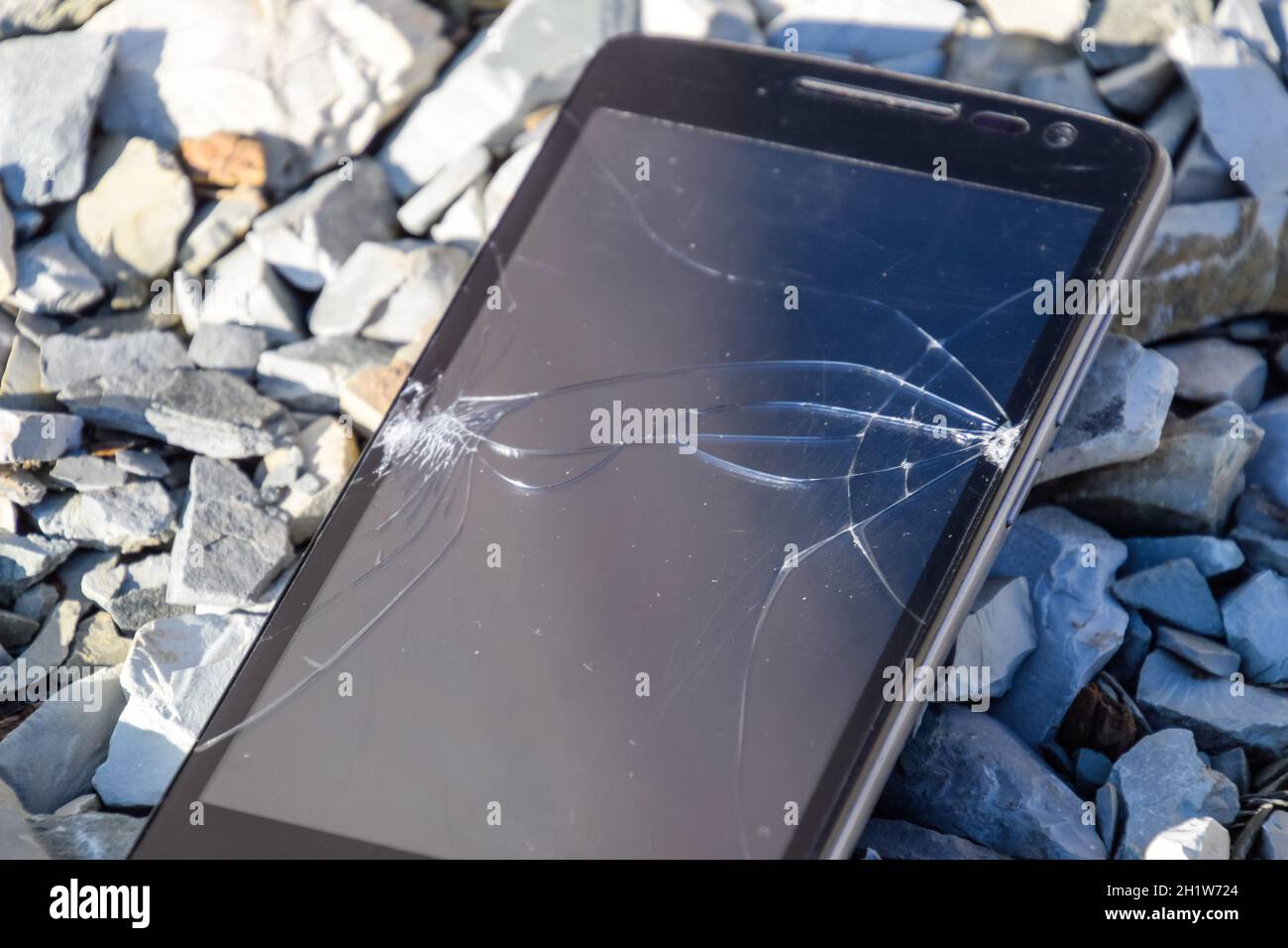 Frustriert Telefon auf den Felsen. Glas zerbrochen auf Felsen auf einem Smartphone. Smartphone fiel und stürzte ab. Stockfoto