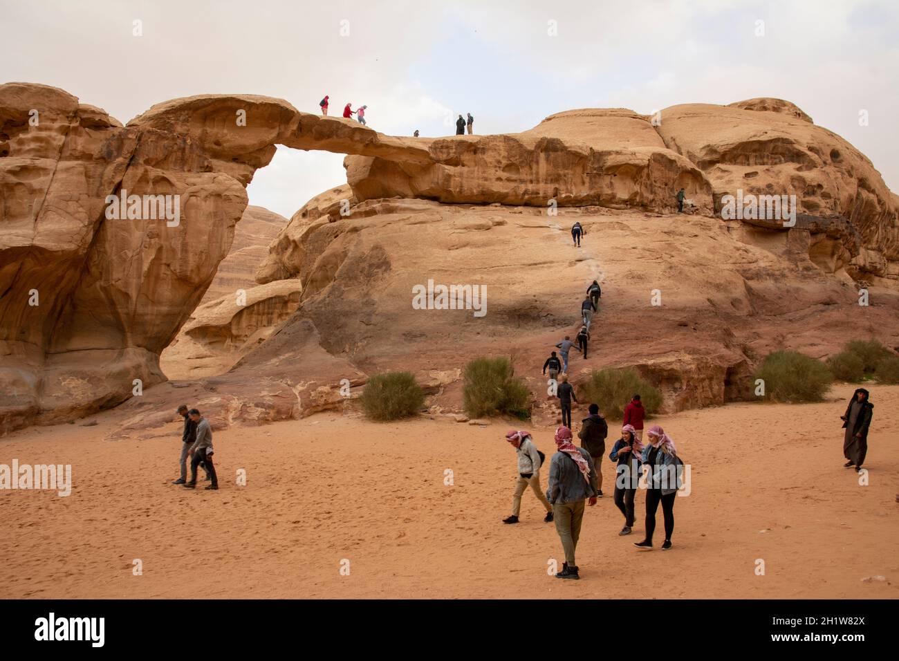 Wadi Rum, Jordanien, März 2020: Menschen, Touristen, Klettern an der um Frouth Natural Rock Bridge Stockfoto