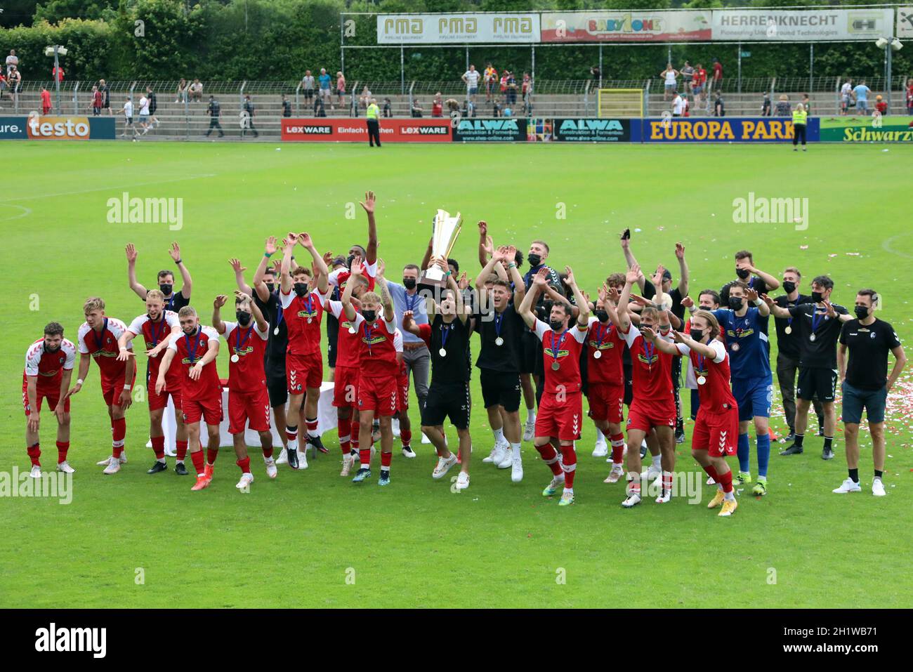 Die Spieler des SC Freiburg II und Trainer Christian Preußer bejuibeln mit dem Meisterpokal den Titel und Aufstieg in die dritte Fußball-Liga Stockfoto