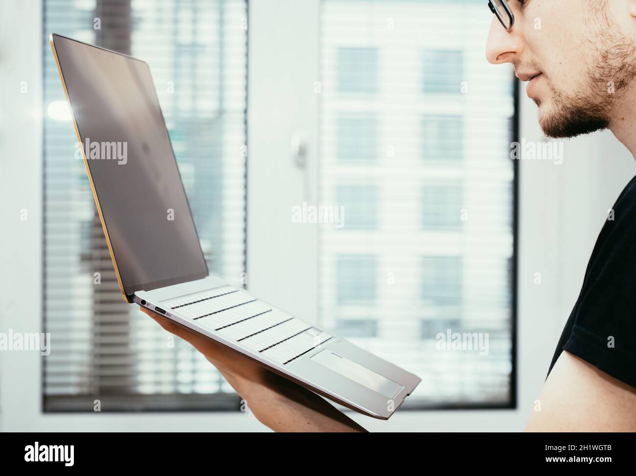 Junge Freiberufler in schwarzen T-Shirts hält eine sehr dünne, elegante Ultrabook Stockfoto